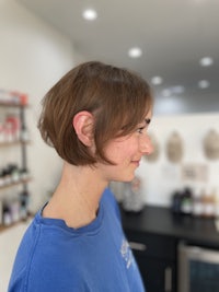 a woman in a blue shirt is standing in a hair salon